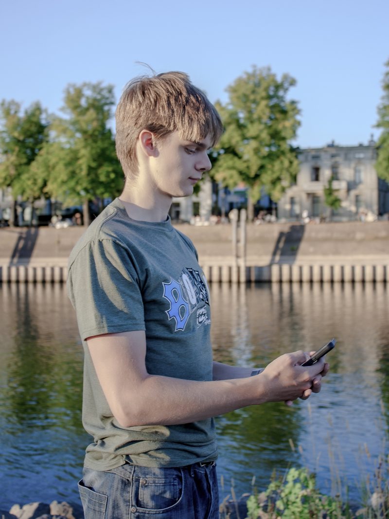 Manou leest buiten een bericht op zijn telefoon