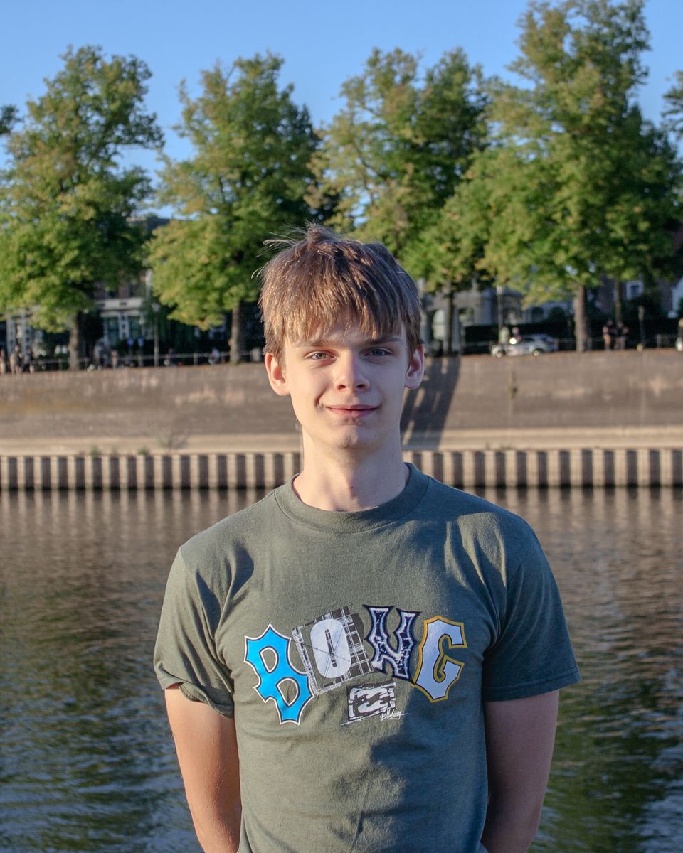 Manou staat buiten aan het water en lacht naar de camera